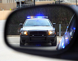 Police car with lights flashing viewed from the driver's mirror and perspective