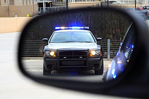 Police car with lights flashing viewed from the driver's mirror and perspective