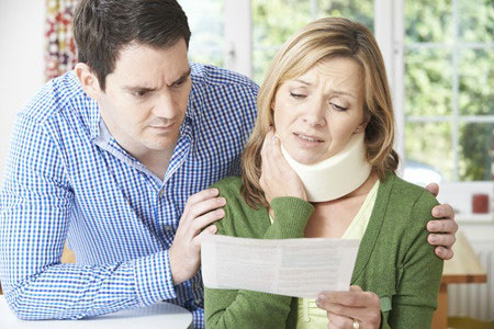 An accident victim is comforted by her husband as they review medical bills due to injuries sustained in a car accident.