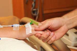 Person holding the hand of an injury victim in the hospital